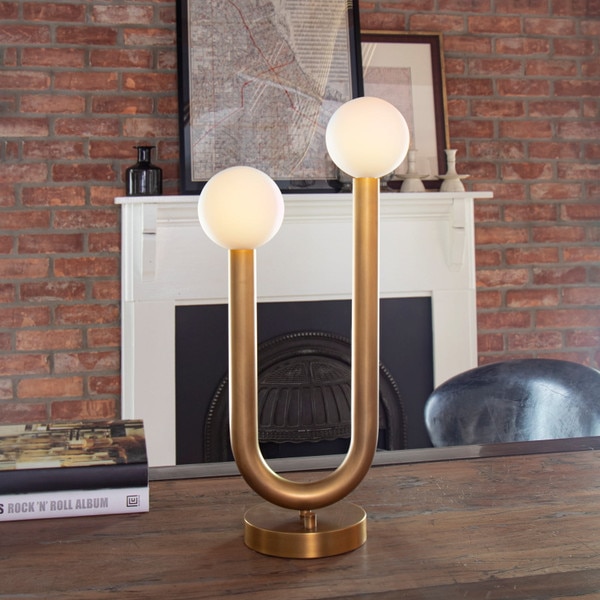 brass table lamp with two arms with circular bulbs on the end on a wooden dining table